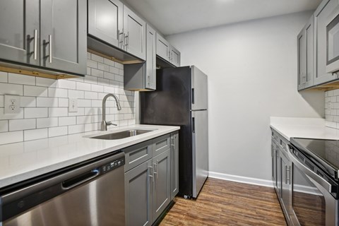 an empty kitchen with stainless steel appliances and white cabinets